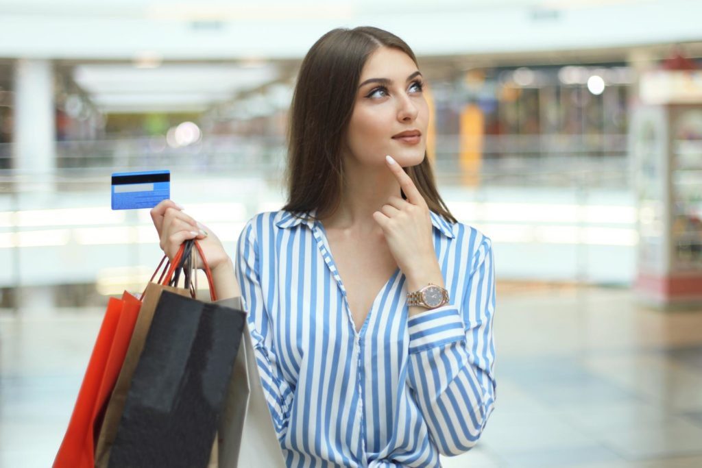 En forbruger, der gransker forskellige cashback-kreditkort, med tankebobler, der repræsenterer hans/hendes udgiftsmønstre og forståelse af cashback-betingelser.